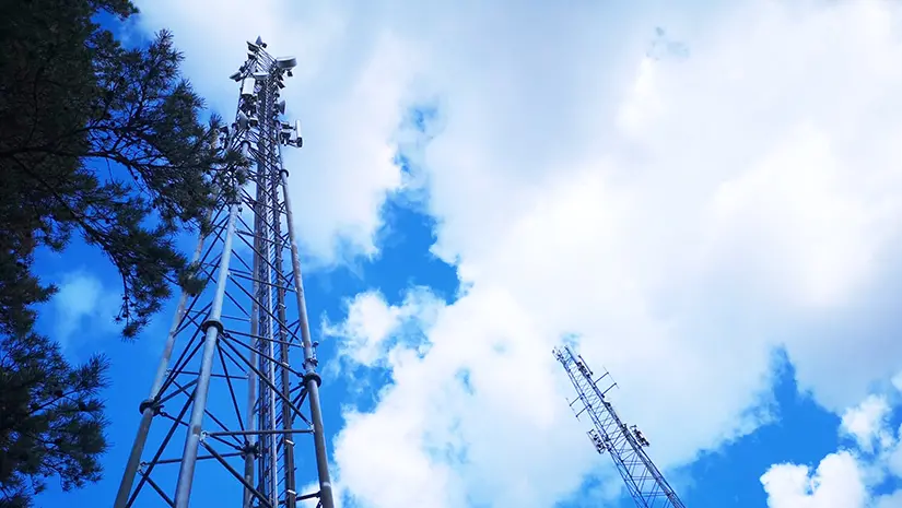 En fibermast mot en blå himmel med vita moln