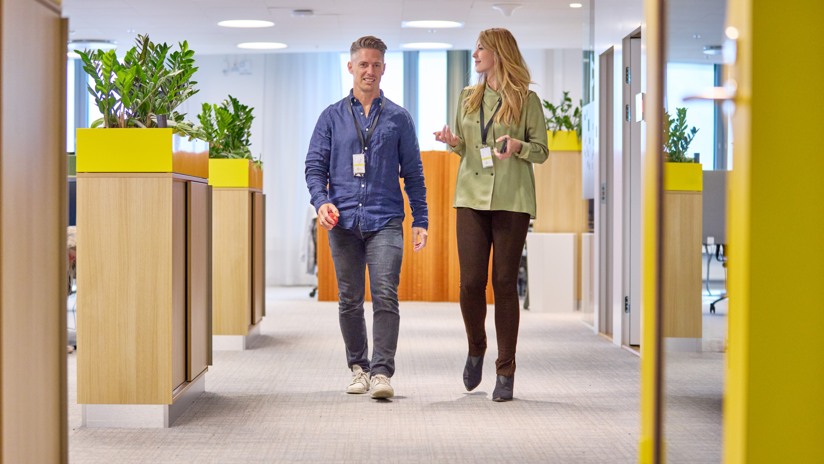 En man och en kvinna kommer gåendes i konstorsmiljö