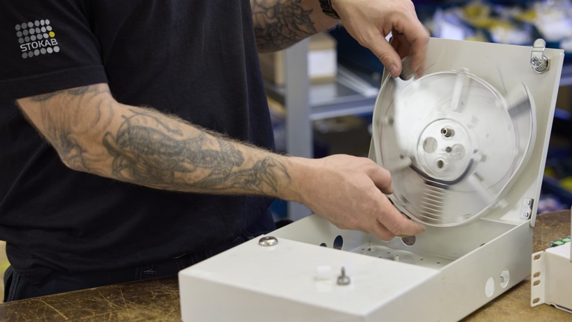 En man arbetar montering i ett plåtskåp som står på ett bord