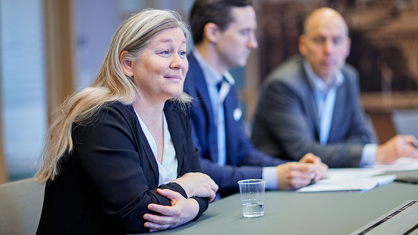 Stokab söker en säkerhetschef där bilden visar en av Stokabs kvinnliga chefer på bild vid ett konferensbord i dialog med andra.